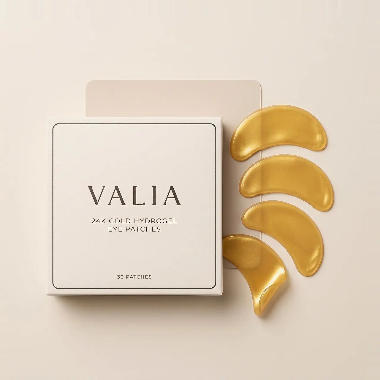The VALIA box open from above, lid set behind, four gold hydrogel crescents fanned beside it.